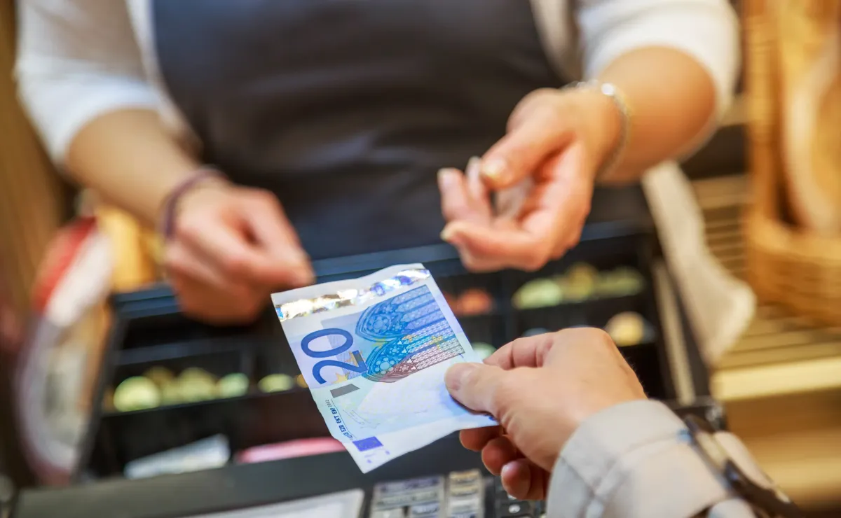 Mujer entregando un billete de 20 euros en un negocio.